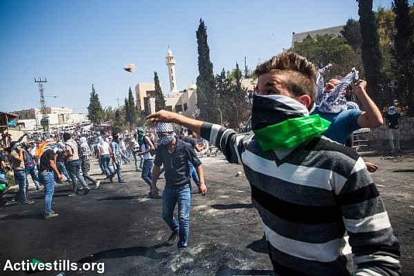Palestinian protesters throw stones during clashes with Israeli forces in the neighbourhood of Abu Dis, east Jerusalem, October 11, 2015. (photo: Yotam Ronen/Activestills.org)