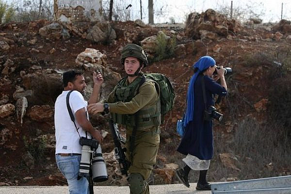 Alla Badarna being pushed back by a soldier as an Israeli photographer is allowed to work without any hindrance. (Photo by Ayman Nubani)