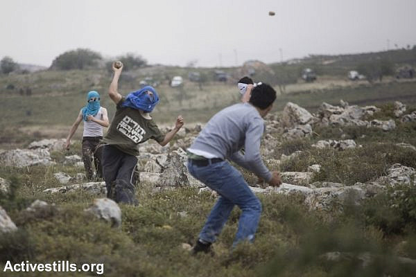 Israeli settlers and Palestinian demonstrators throw stones at each other, after settlers marched onto the lands of the West Bank villages of Deir Jarir and Silwad where villages were protesting the construction on their land by members of the nearby Jewish settlement of Ofra, May 3, 2013. (photo: Oren Ziv/Activestills.org)