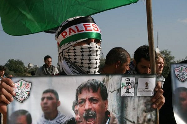 A resident of Bil'in protests with a poster of Ziad Abu Ein, who died during an unarmed demonstration last year. (photo: Haggai Matar)