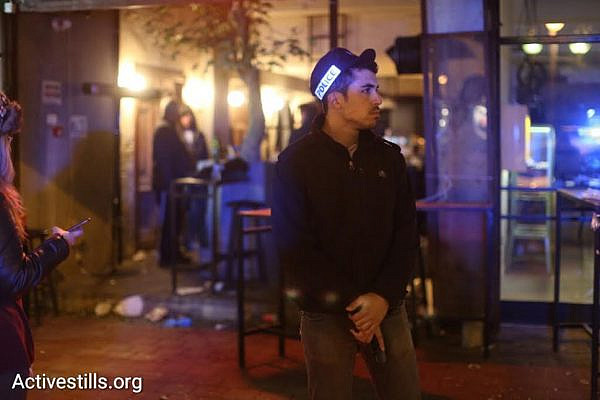 A policeman looks on as Police forensic officers, spokespeople and commanders inspect the scene of the shooting attack in central Tel Aviv, Friday, January 2, 2016. (photo: Oren Ziv/Activestills.org)