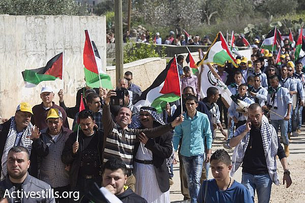 Palestinians, Israelis and internationals march through the West Bank village of Bil’in, protesting Israel’s expropriation of village land with the separation barrier, February 19, 2016. (Oren Ziv/Activestills.org)