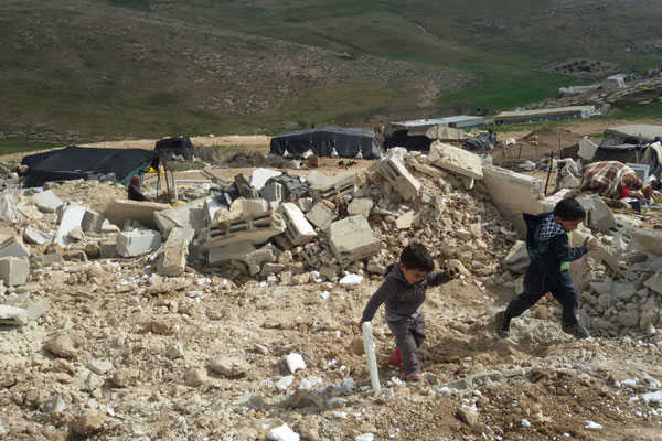 Palestinian children play in the rubble left after the Israeli military demolished 24 Palestinian structures in Khirbet Jenbah, which is part of what the army calls ‘Firing Zone 918,’ February 2, 2016. (Nasser Nawaj’ah/B’Tselem)