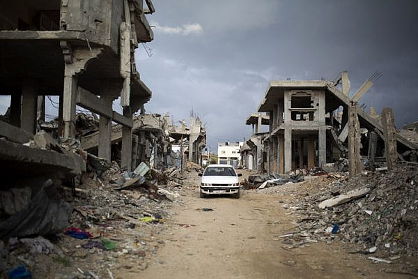 Palestinians drive through a destroyed quarter of Al Shaaf area in Al Tuffah, east of Gaza City, March 21, 2015. The rubble from destroyed apartment buildings is often recycled into low-quality cement. (Anne Paq/Activestills.org)