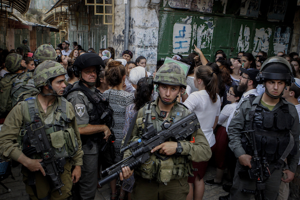 Israeli soldiers escort Jewish settlers as they tour the Old City of the occupied West Bank city of Hebron, June 4, 2016. The Israel army has enforced segregation in the city for over two decades, restricting residents’ movement according to their religion. (Wisam Hashlamoun/FLASH90)