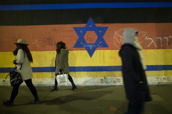 People walk by a mural depicting a combination of the Israeli and German flag on the Berlin wall, March 13, 2016. (Noam Revkin Fenton/Flash90)