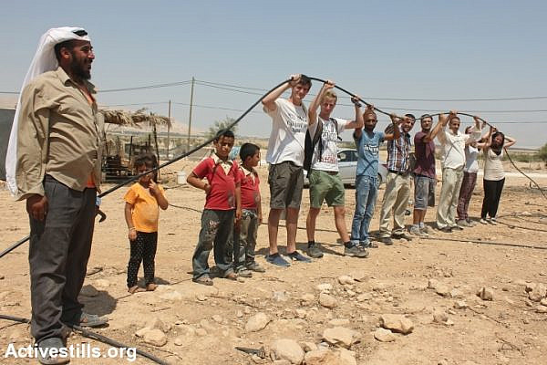 Palestinians and international activists connect a water pipe to Palestinian families' homes in Fasayil, Jordan Valley, August 17, 2013. (Ahmad Al-Bazz/Activestills.org)