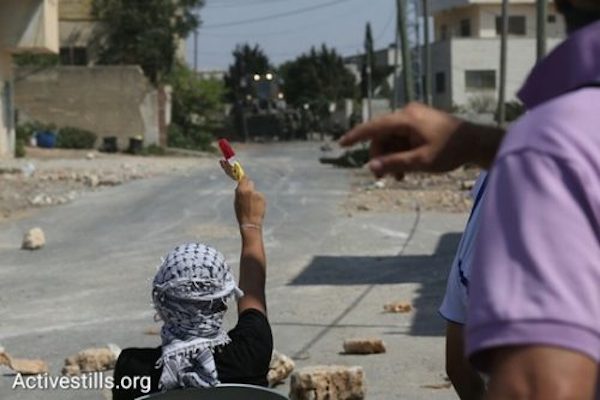 Popsicle against the occupation. The protestors offer popsicles to the soldiers sitting across from them. Qaddum, August 28, 2016. (Oren Ziv/Activestills.org)