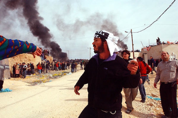 An Israeli settler throws stones at armed forces in the illegal outpost of Amona, Jan. 1, 2006 (file photo). Clashes broke out shortly after the High Court gave the green light to dismantle half a dozen homes in the area. (Yossi Zamir/Flash90)