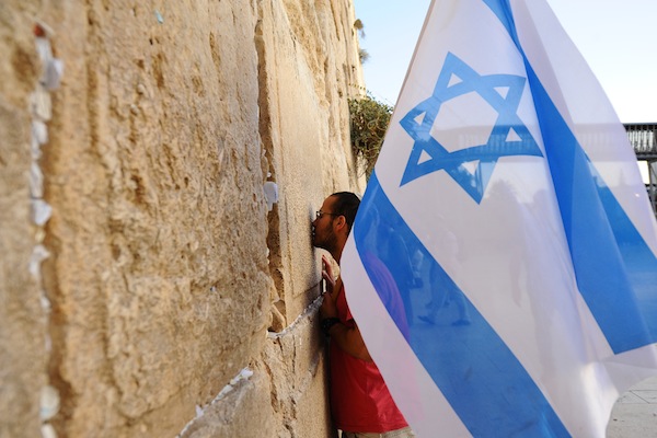 A man holds an Israeli flag during a march in support of the city of Jerusalem at the Western Wall, Jerusalem's Old City on October 22, 2015, following a wave of attacks by Palestinians. (Mendy Hechtman/Flash90)