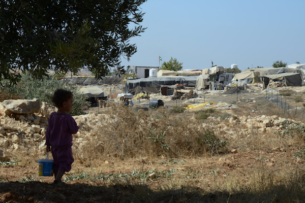 A Palestinian child looks out over his village, Susiya, October 2016. (Gili Getz). The village is under threat of demolition to make way for a neighboring Jewish settlement, also called Susiya.