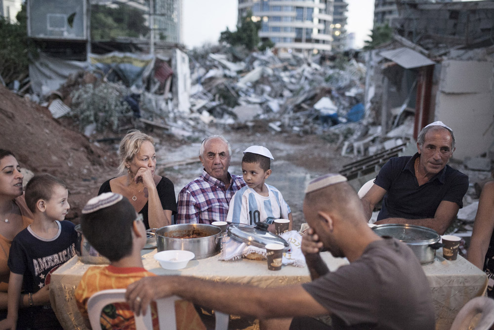 Three families hold an improvised, outdoor Shabbat dinner after their homes were demolished following a years-long struggle against eviction without proper compensation, Givat Amal, Tel Aviv, September 19, 2014. (Activestills.org)