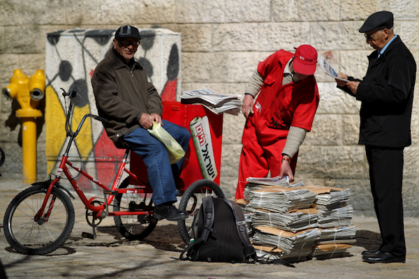 An ‘Israel Hayom’ employee hands out free copies of the daily newspaper in Jerusalem. (Nati Shohat/Flash90)