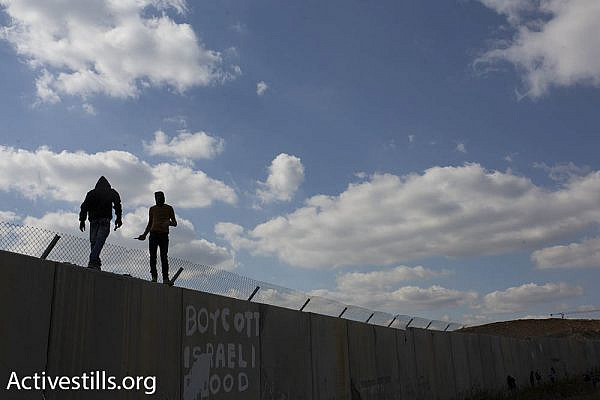 Palestinian youths climb the Israeli separation barrier in Bil’in, February 17, 2017. (Oren Ziv/Activestills.org)