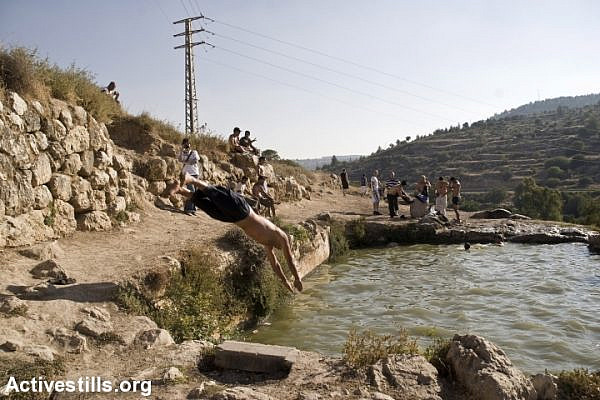 Israelis swim in a spring belonging to the destroyed Palestinian village of Walajeh, near Jerusalem. (Anne Paq/Activestills.org)