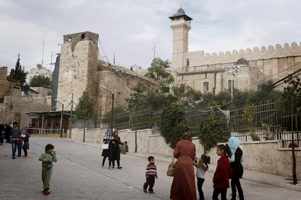 Palestinians walk by the Tomb of the Patriarchs in the occupied West Bank city of Hebron. (Miriam Alster/Flash90)