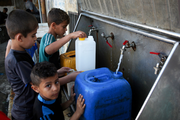 Palestinian children fill jerrycans with drinking water in the Rafah Refugee Camp in the southern Gaza Strip, June 11, 2017. (Abed Rahim Khatib/Flash90)
