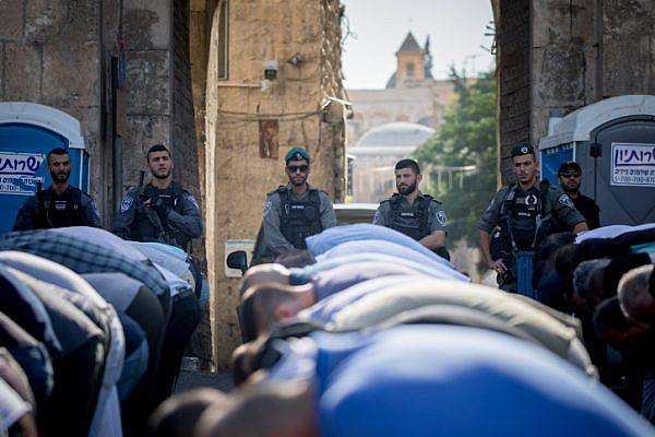 Israeli police officers guard as Muslim worshippers perform a prayer at the Lion's Gate, outside the Temple Mount, in Jerusalem's Old City. Metal detectors were placed at gates to the Temple Mount, and the Muslim worshippers refused to pass through them. The Temple Mount was reopened following last weeks terror attack when two Israeli Arabs opened fire and killed two Israeli police men. July 19, 2017. (Yonatan Sindel/Flash90