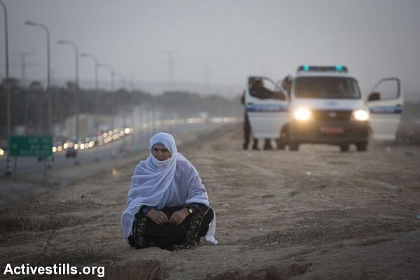 A Bedouin woman from the unrecognized village of Al-Araqib sits in front of an Israeli police van. Israel has demolished al-Araqib over 100 times. (Illustrative photo by Oren Ziv/Activestills.org)