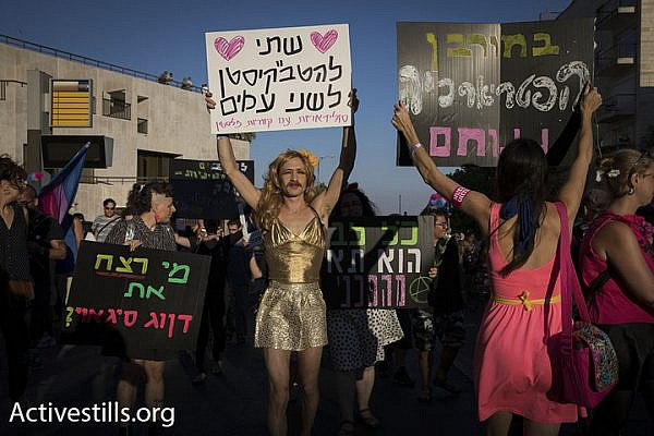 A participant in the Jerusalem pride parade holds up a sign in solidarity with LGBTQ Palestinians, Jerusalem, August 3, 2017. (Activestills.org)
