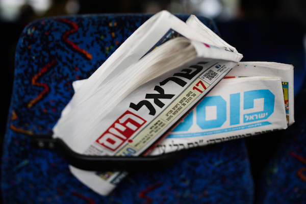 Illustrative photo of Israeli newspapers stuffed into the back of a bus seat, (Maxim Dinshtein/Flash90)