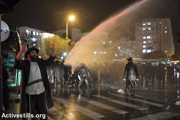 Police fire "Skunk" water against ​ultra-Orthodox Jews who are blocking a main road during a demonstration, protesting against the imprisonment of their fellow Haredim, who have been detained by the army for not enlisting, West Jerusalem, November 26, 2017. (Oren Ziv/Activestills.org)