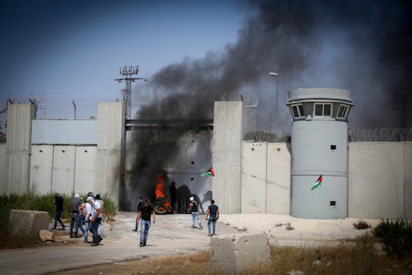 Palestinian youths burn tires next to Israel's separation wall in Qalandiya, in between Jerusalem and Ramallah, West Bank. (Flash90)