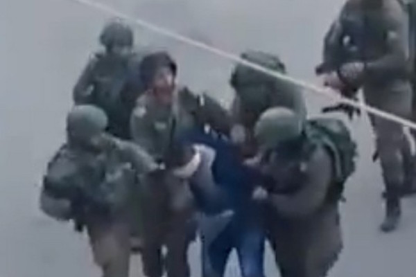 A screenshot from a video of soldiers beating a Palestinian detainee in Hebron.