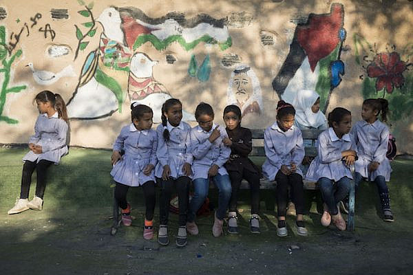 Palestinian schoolgirls sit outside the school in Khan al-Ahmar, which held its first day of school a month and a half early in order to prevent its planned demolition, July 16, 2018. (Oren Ziv)