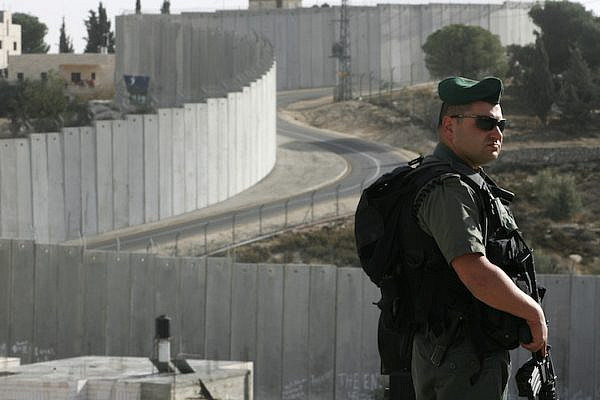 An Israeli Border Police officer is seen in front of Israel's separation barrier in Abu Dis, West Bank. (Kobi Gideon/Flash90)