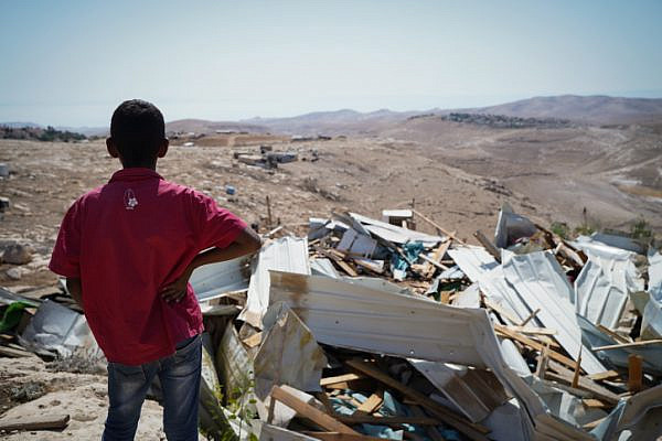 A child looks on at the remains of demolished homes in the Palestinian village of Khan al-Ahmar, July 4, 2018. (Yaniv Nadav/Flash90)