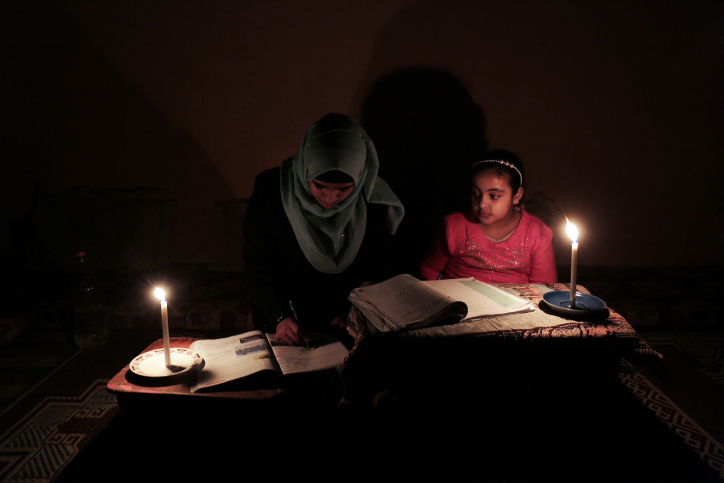Palestinian children do their homework by candlelight at their home in Rafah refugee camp, in the southern Gaza Strip, on February 15, 2018. (Abed Rahim Khatib/ Flash90)