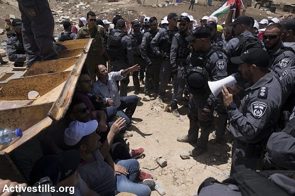 Palestinian, foreign, and Israeli activists try to block an Israeli bulldozer preparing for the demolition of Khan al-Ahmar, July 4, 2018. (Oren Ziv/Activestills.org)