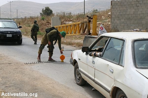 Israeli soldiers inspect Palestinian cars at the Beit Furik checkpoint, near Nablus, West Bank, May 27, 2015. (Ahmad Al-Bazz/Activestills.org)