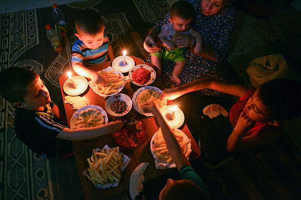 A Palestinian family eats dinner by candlelight at their home in Rafah, in the southern Gaza Strip, during a power outage on June 12, 2017. (Abed Rahim Khatib/Flash90)