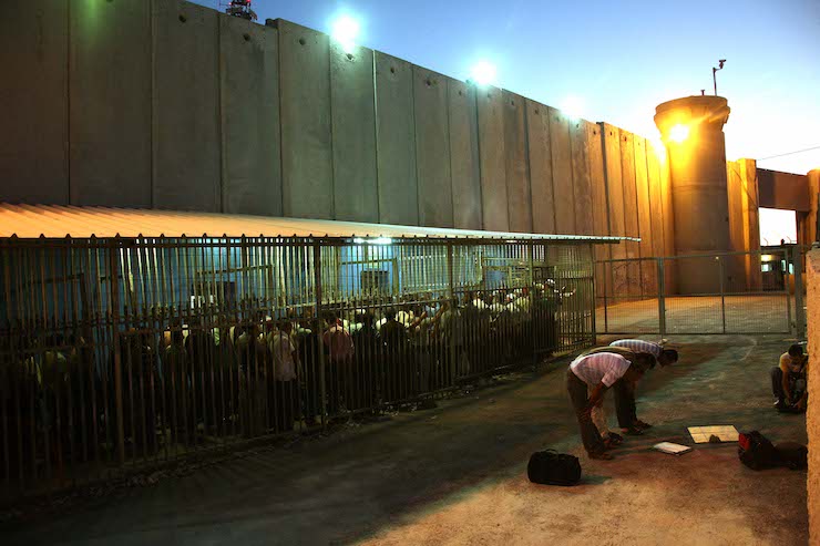Palestinian workers wait to cross a checkpoint to work in Israel at the separation barrier in the West Bank city of Bethlehem, on August 23, 2010. (Najeh Hashlamoun/Flash 90)