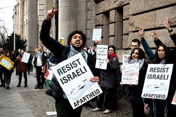 Demonstrators hold signs outside a Berlin courthouse on the opening day of the trial of three BDS activists charged with assault for interrupting an Israeli MK during a lecture in 2017, March 4 2019. (Magda Stefanenco)