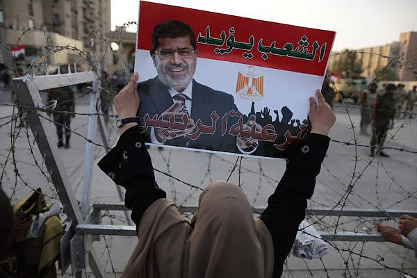 A supporter of Egypt's ousted president, Mohamed Morsi, holds a poster of him with Arabic writing reading "The people support the president," Cairo, Egypt, on July 06, 2013. (Wissam Nassar/Flash90)