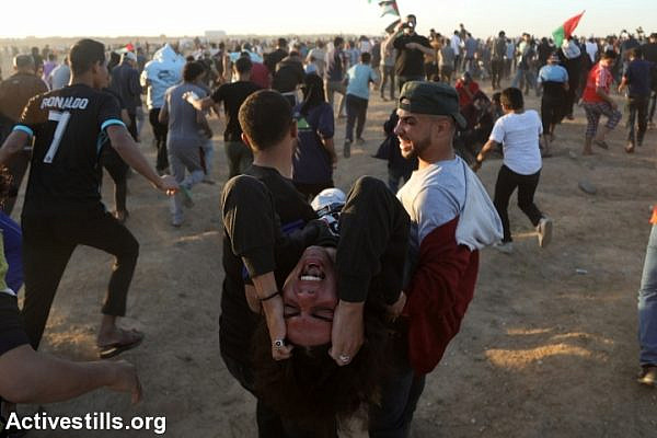 Palestinians evacuate a protester during a Great Return March protest near the Gaza fence, east of Gaza City, November 2, 2018. (Mohammed Zaanoun/Activestills.org)