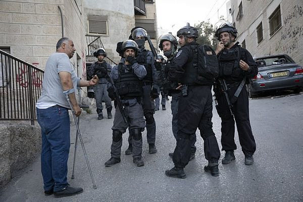 Muhammad Abu Hummus, a political activist from the East Jerusalem neighborhood of Issawiya, is seen speaking to Israeli riot police during a raid on the neighborhood. (Oren Ziv/Activestills.org)