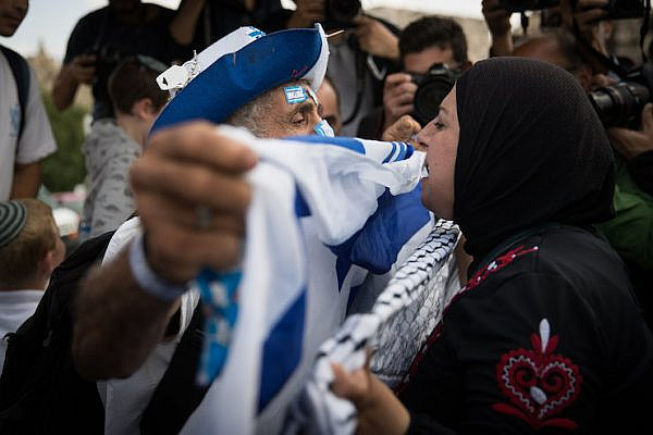 A Jewish Israeli man holding an Israeli flag confronts a Palestinian woman holding a kaffiyeh on the sidelines of the ultra-nationalist "Jerusalem Day" march, May 13, 2018. (Yonatan Sindel/Flash90)