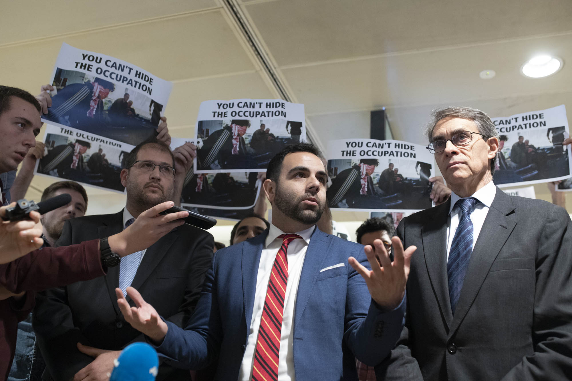 Human Rights Watch Israel and Palestine Director Omar Shakir speaks to press ahead of his deportation from Israel, flanked by HRW head Kenneth Roth, right, and attorney Michael Sfard, left, November 25, 2019 (Oren Ziv/Activestills.org).