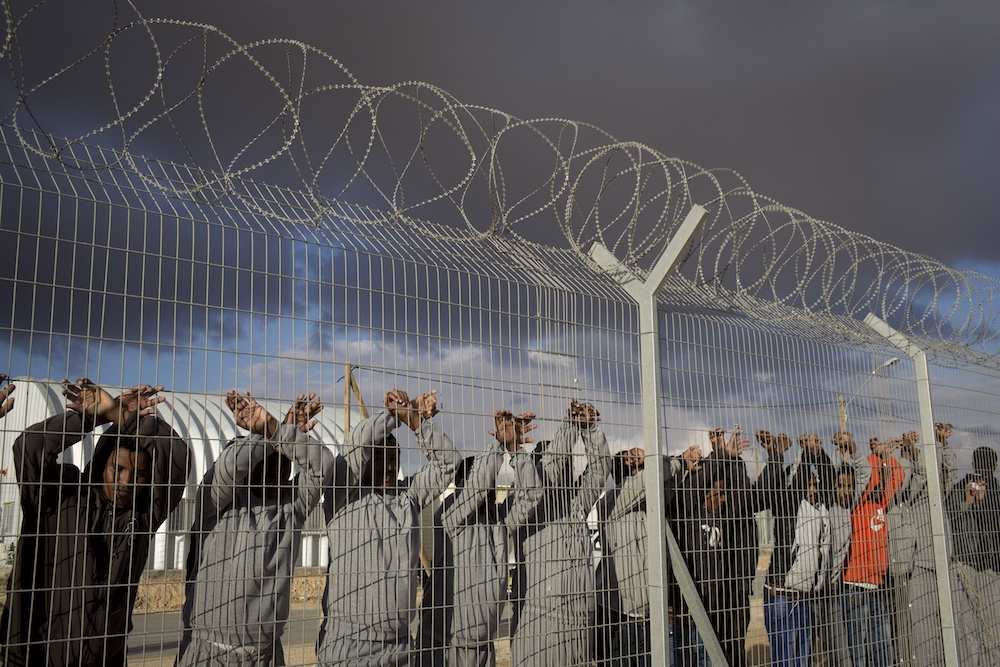 African asylum seekers jailed in Holot detention center protest behind the prison's fence, February 17, 2014. (Oren Ziv)