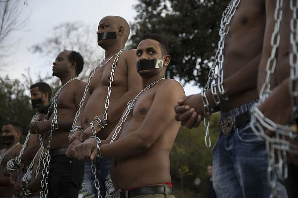 Asylum seekers from Sudan and Eritrea hold mock slave auctions outside the embassy of Rwanda in Herzliya, near Tel Aviv, during a protest against the Israeli government's plan to deport African asylum seekers to third countries in Africa, January 22, 2018. (Oren Ziv/Activestills.org)