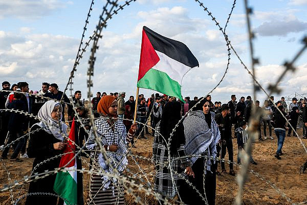 Palestinian demonstrators stand alongside the Gaza border fence during a protest, east of Rafah in the southern Gaza Strip, December 6, 2019. (Abed Rahim Khatib/Flash90)