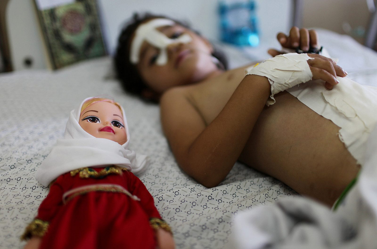 Four-year-old Palestinian girl Shayma Al-Masri, who was wounded in an Israeli air strike that killed her mother and two of her siblings, lies next to her doll as she receives hospital treatment in Gaza City, July 14, 2014. (Emad Nassar/Flash90)