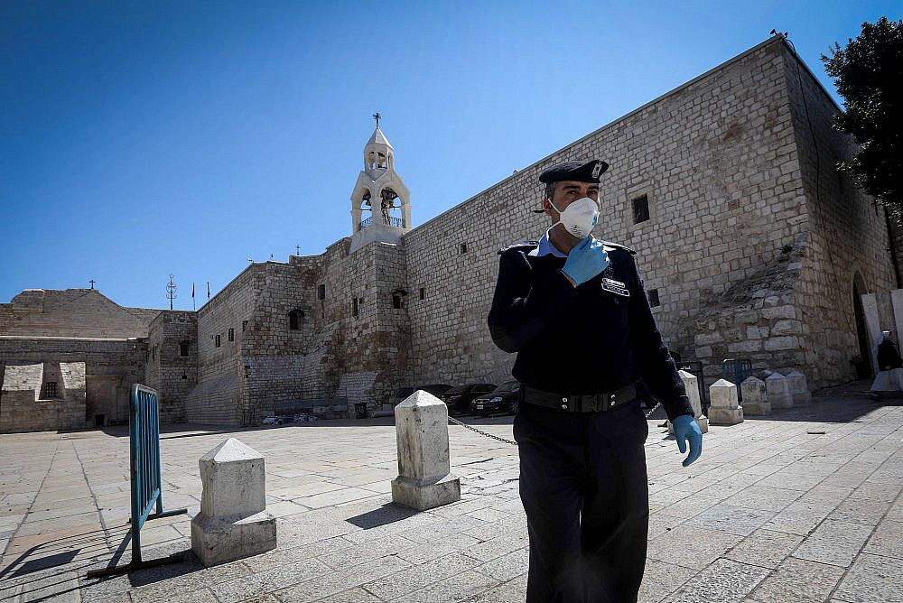 A Palestinian police officer wears a mask to protect himself from coronavirus stands outside the closed Church of the Nativity in the West Bank city of Bethlehem, March 8, 2020. (Wisam Hashlamoun/Flash90)