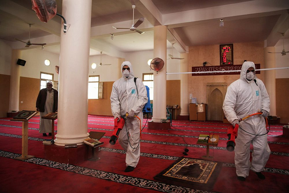 Palestinian Health workers spray disinfectant as a precaution against the new coronavirus in the Al-Omari Mosque in Gaza City. March 15, 2020. (Ail Ahmed/Flash90)