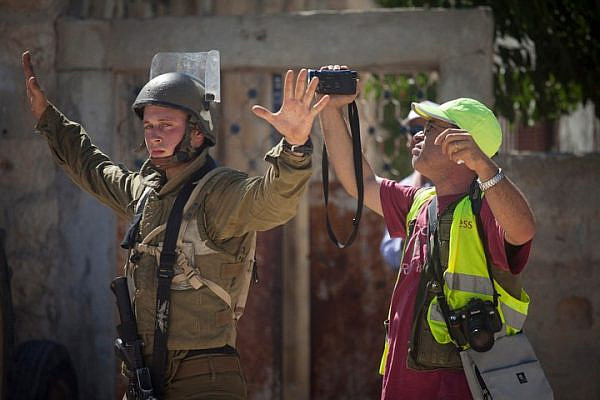 An illustrative photo of an Israeli soldier blocks a journalist from filming in the West Bank village of Nabi Saleh. (Flash90)