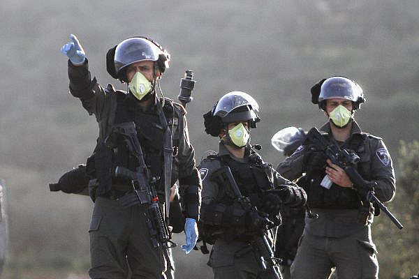 Israeli Border Police officers wear face masks during clashes with Palestinian protesters in Jabal Al-Arma, near the town of Beita, West Bank, March 11, 2020. (Nasser Ishtayeh/Flash90)